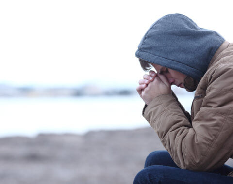 Young man sits with head in hands