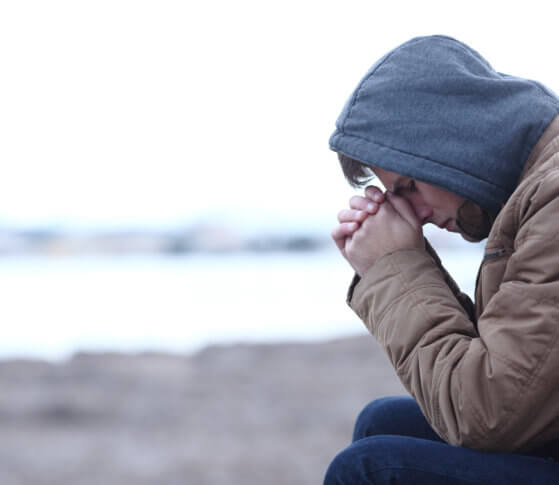 Young man sits with head in hands