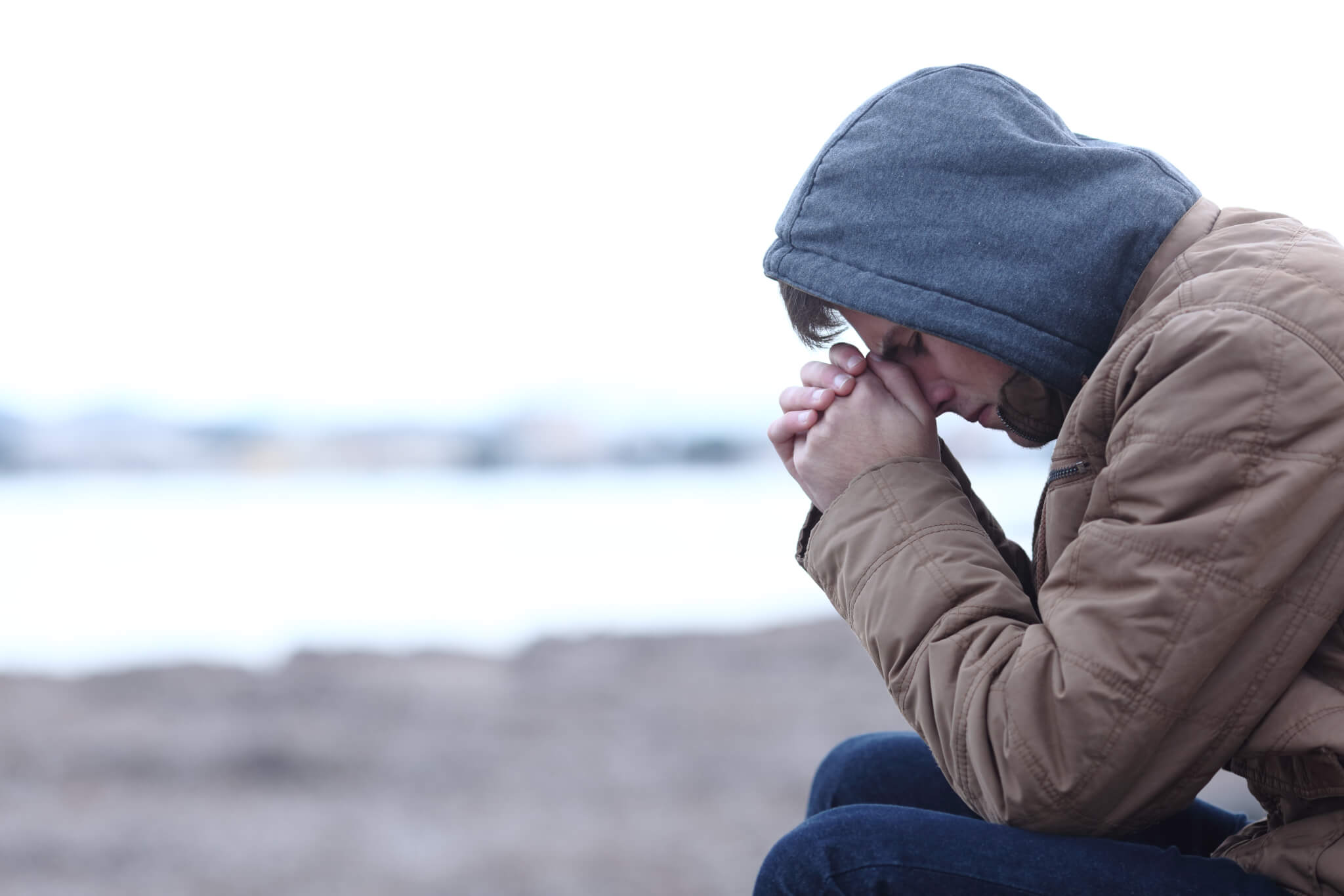 Young man sits with head in hands